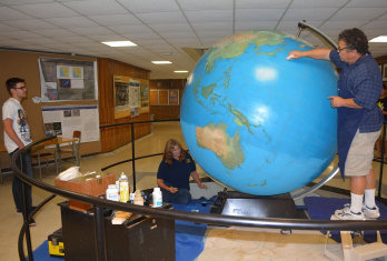 Art conservator, Dimitri Nedelcu is applying a hand polish to the globe to protect the finish, as his wife, Georgiana Nedelcu restores 
the southern pole.